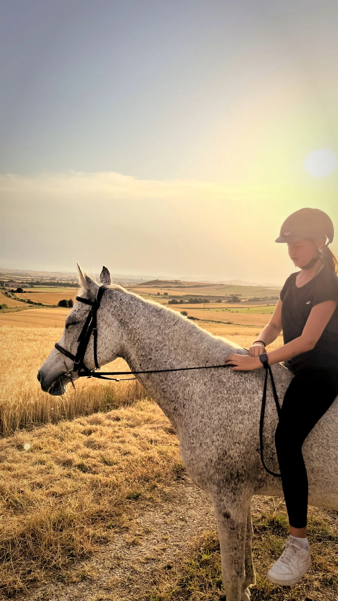 Joven cabalgando solitaria en hora dorada con paisaje alavés
